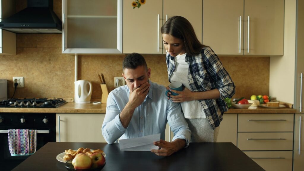 Couple looking stressed over paperwork at a kitchen table